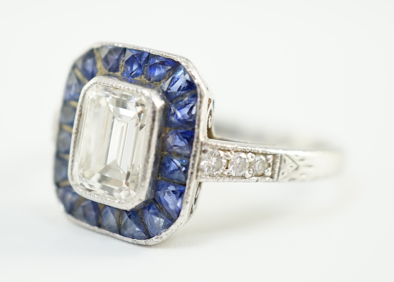 A 1920's platinum and millegrain set single stone emerald cut diamond and sapphire set rectangular cluster ring